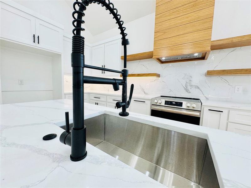 Kitchen view of open shelves, white cabinets, light stone countertops, and electric stove Kitchen view of open shelves, white cabinets, light stone countertops, and electric stove