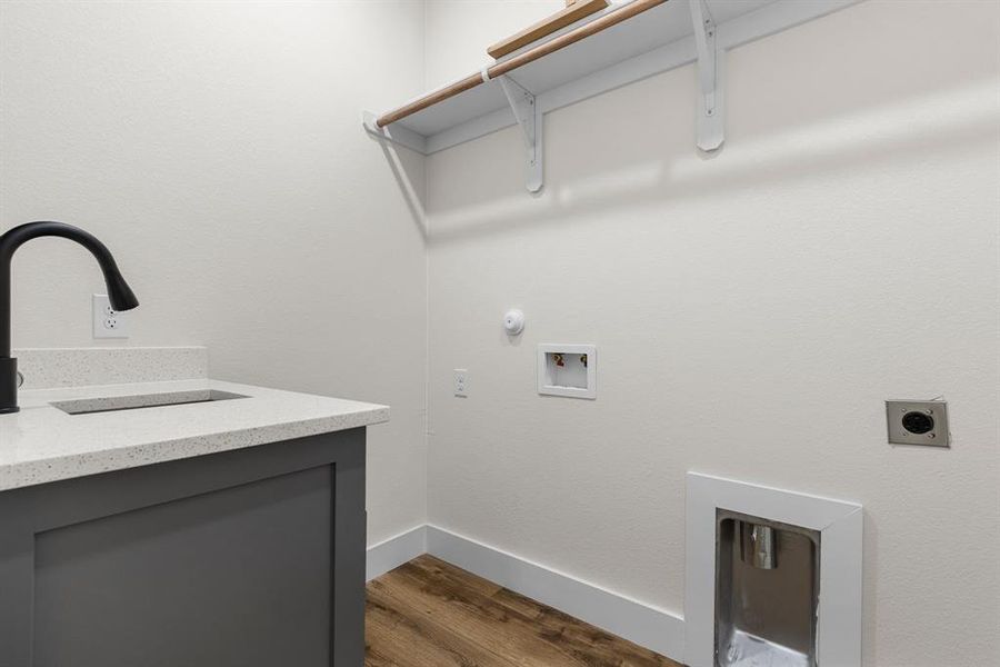 Clothes washing area with hookup for an electric dryer, washer hookup, gas dryer hookup, sink, and dark hardwood / wood-style floors