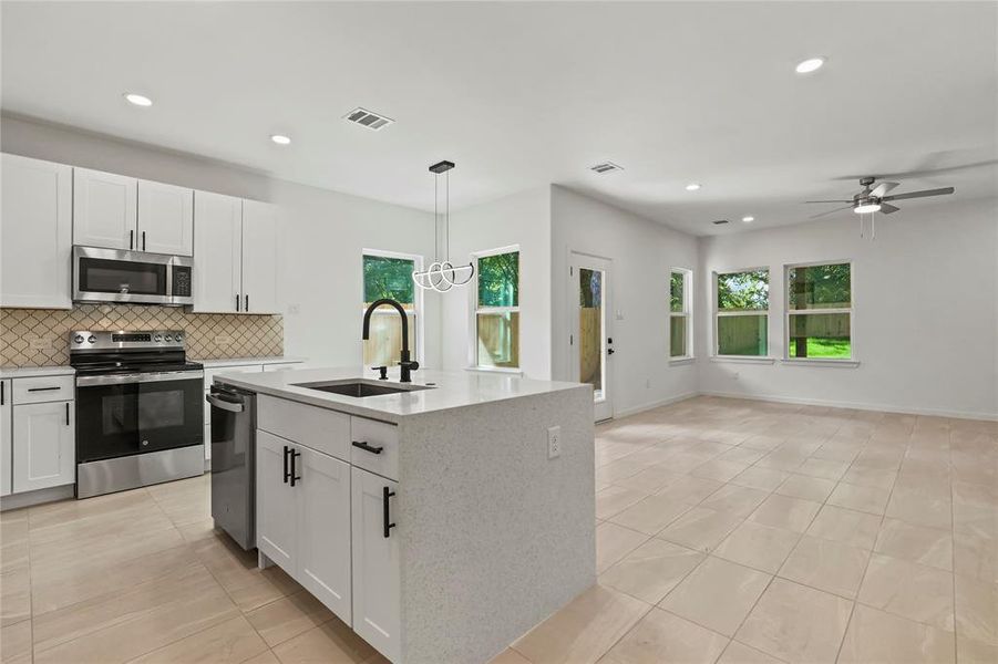 Kitchen with light tile patterned floors, appliances with stainless steel finishes, backsplash, white cabinets, and recessed lighting