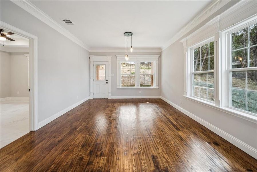 Unfurnished dining area with crown molding, a healthy amount of sunlight, and dark hardwood / wood-style floors