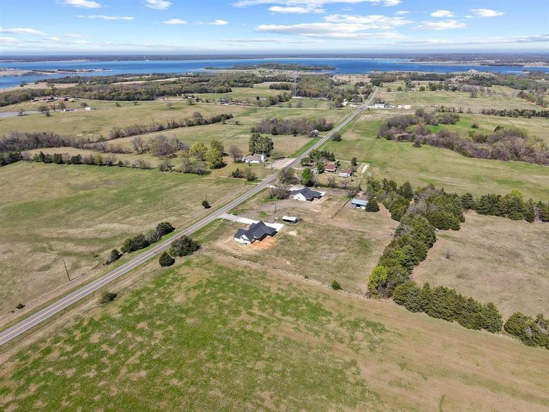 Expansive property featuring vast open fields, a long paved road, and distant water views