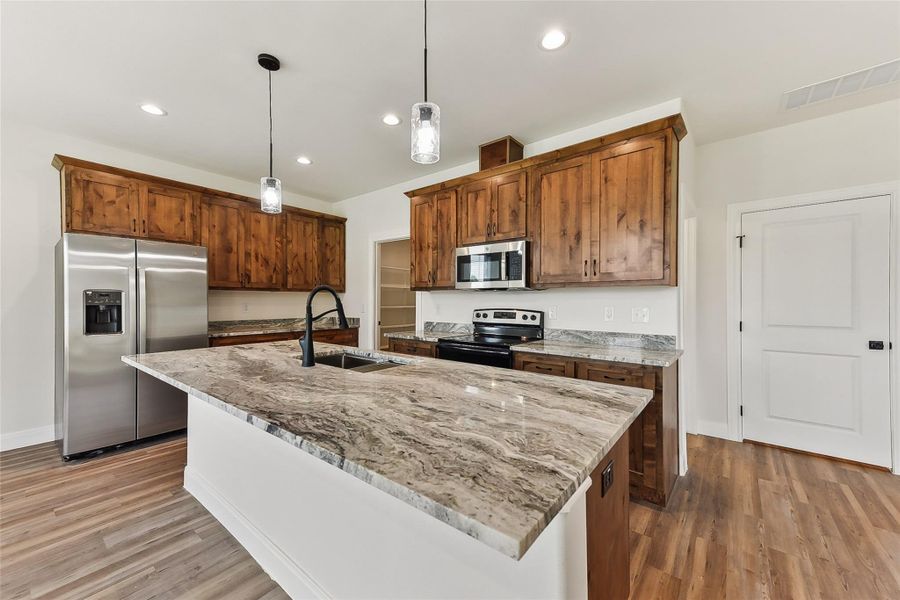 Kitchen featuring light wood-type flooring, visible vents, appliances with stainless steel finishes, and a sink Kitchen featuring light wood-type flooring, visible vents, appliances with stainless steel finishes, and a sink