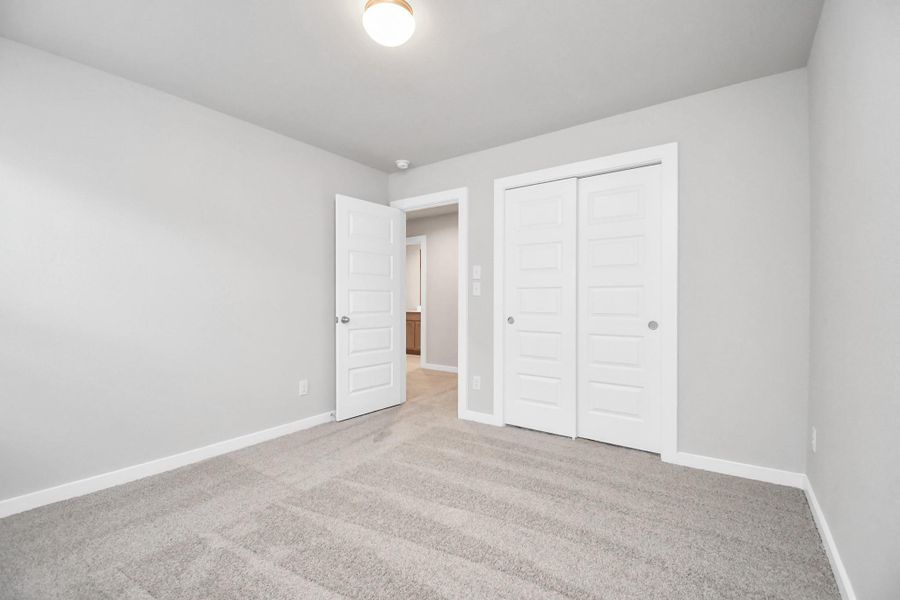 Secondary bedroom features plush carpeting, large windows that let in plenty of natural light, bright paint, and spacious closets. Sample photo of completed home with similar floor plan. Actual colors and selections may vary.