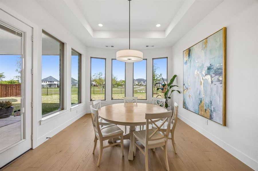 Dining area featuring light wood-type flooring, recessed lighting, and a tray ceiling