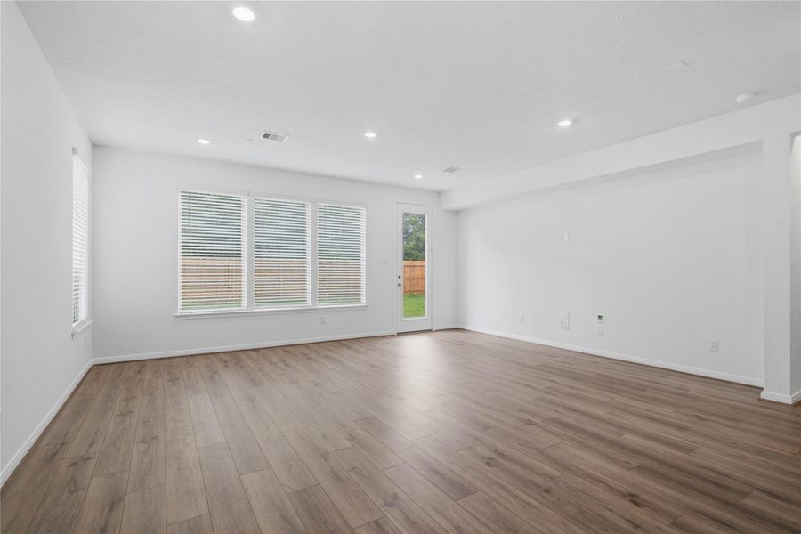 This bright and airy Great Room offers a spacious layout ideal for both relaxing evenings and lively gatherings. Designed for comfort and connection, it features vinyl plank flooring, large windows with blinds, soaring ceilings, recessed lighting, and seamless access to the stunning kitchen and dining—perfect for everyday living and entertaining alike.