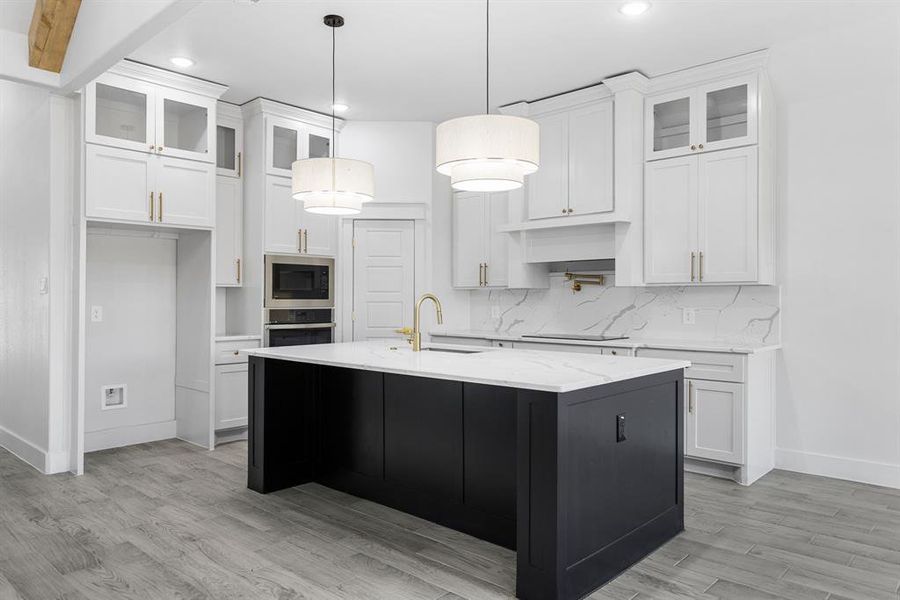 Kitchen featuring sink, white cabinets, a center island with sink, and appliances with stainless steel finishes