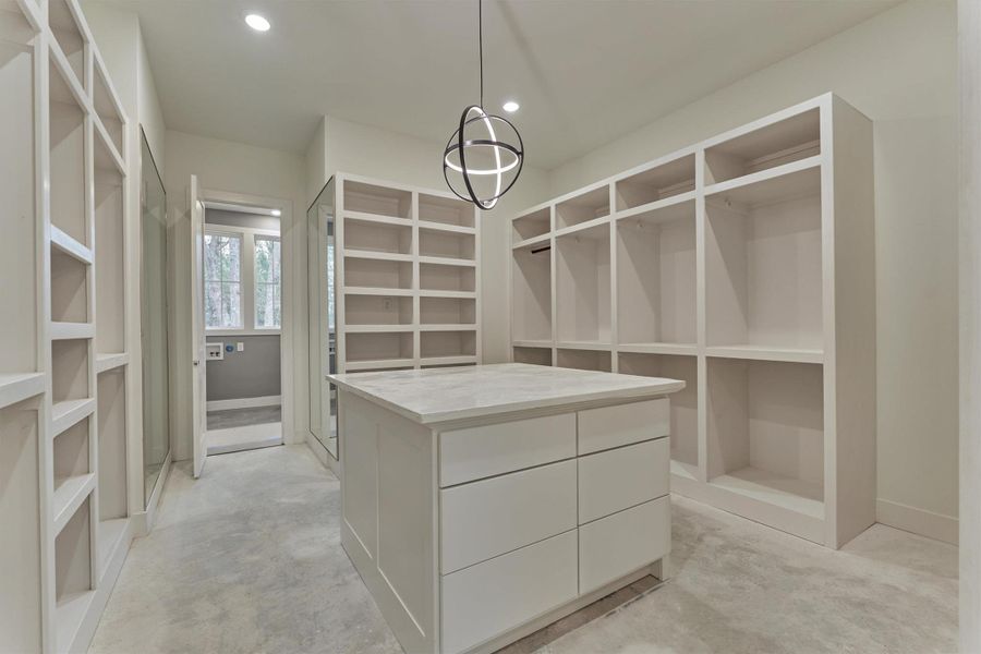 Expansive primary closet with custom built-ins, a marble-topped island, and full-length mirrors—beautifully designed for effortless organization and everyday luxury.