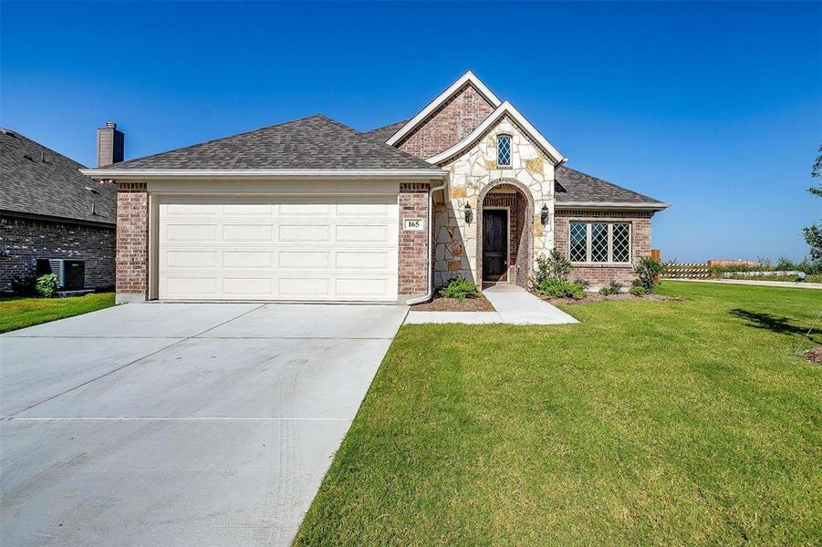 View of front of property featuring a garage and a front lawn