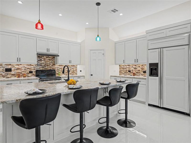 Kitchen featuring paneled built in refrigerator, pendant lighting, black / electric stove, and a kitchen bar