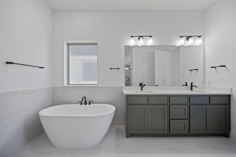 Bathroom with tile walls, tile patterned flooring, vanity, and a tub to relax in