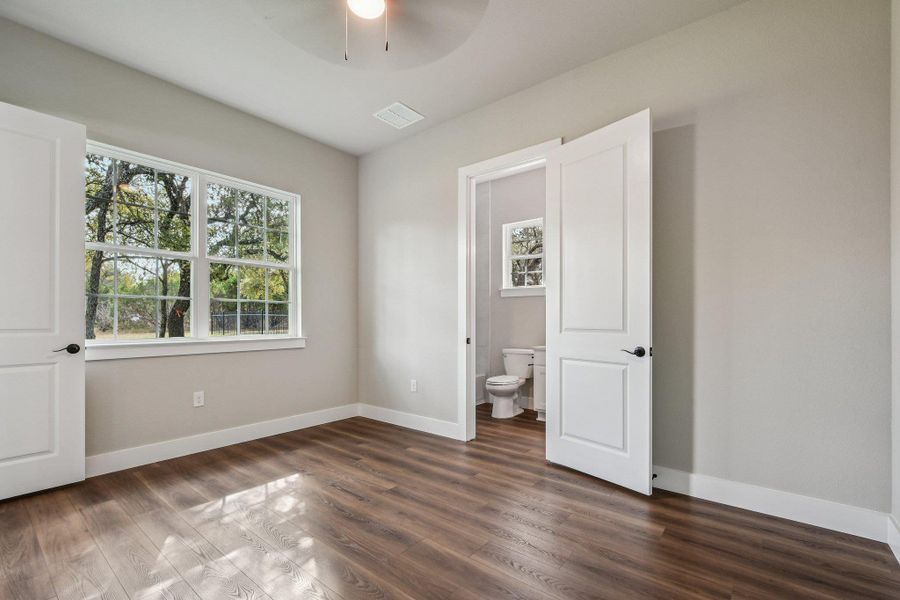 Unfurnished bedroom featuring dark wood finished floors, connected bathroom, and ceiling fan