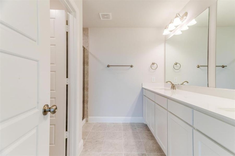 Bathroom with vanity, tile patterned floors, and a shower with shower door
