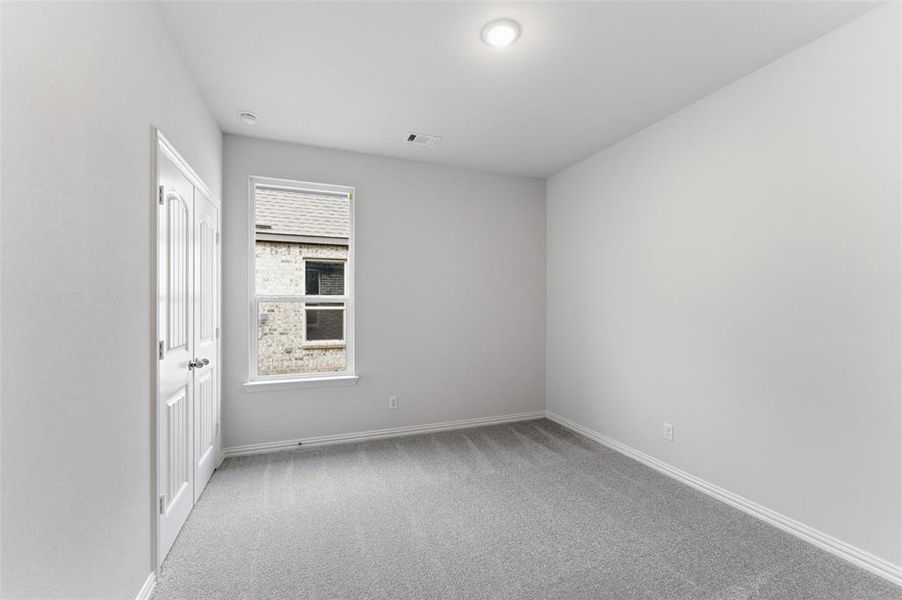 Neutral-toned room featuring light gray carpeting and white baseboards