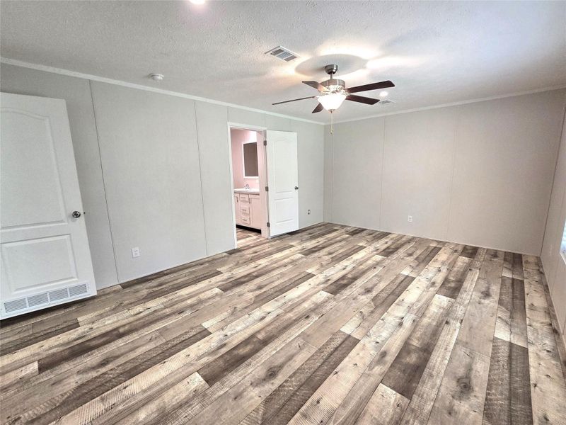 This spacious master bedroom boasts sleek wood-style flooring, a modern ceiling fan, and direct access to an elegant ensuite bathroom, offering a perfect blend of comfort and style. This spacious master bedroom boasts sleek wood-style flooring, a modern ceiling fan, and direct access to an elegant ensuite bathroom, offering a perfect blend of comfort and style.