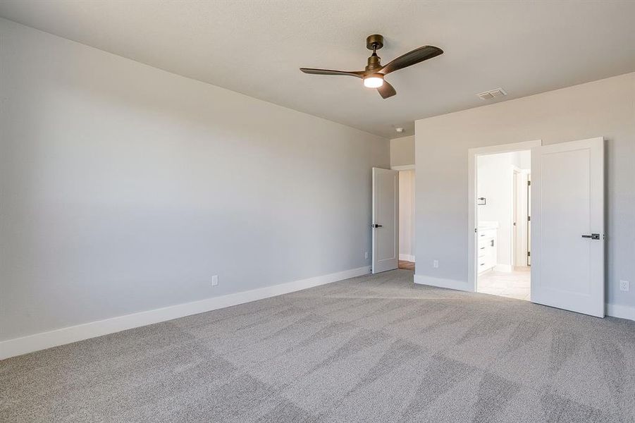 Unfurnished bedroom featuring light colored carpet, ceiling fan, and ensuite bathroom