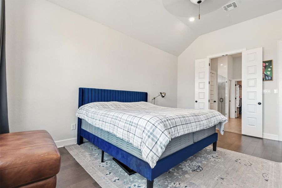 Bedroom featuring dark wood-style floors, lofted ceiling, and a ceiling fan Bedroom featuring dark wood-style floors, lofted ceiling, and a ceiling fan