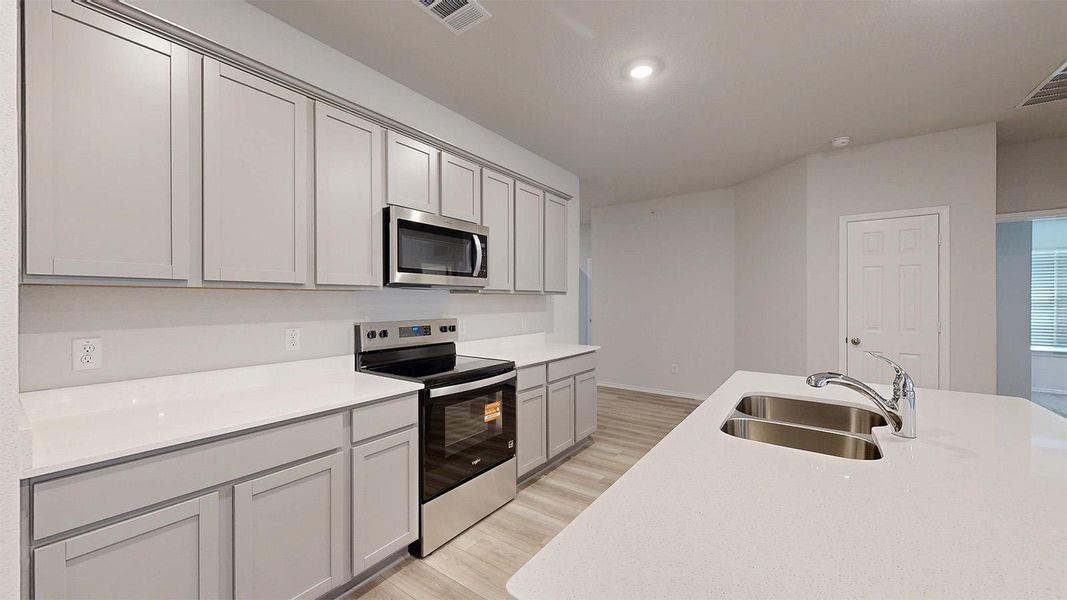 A well-equipped kitchen boasts light cabinetry and stainless steel appliances.
