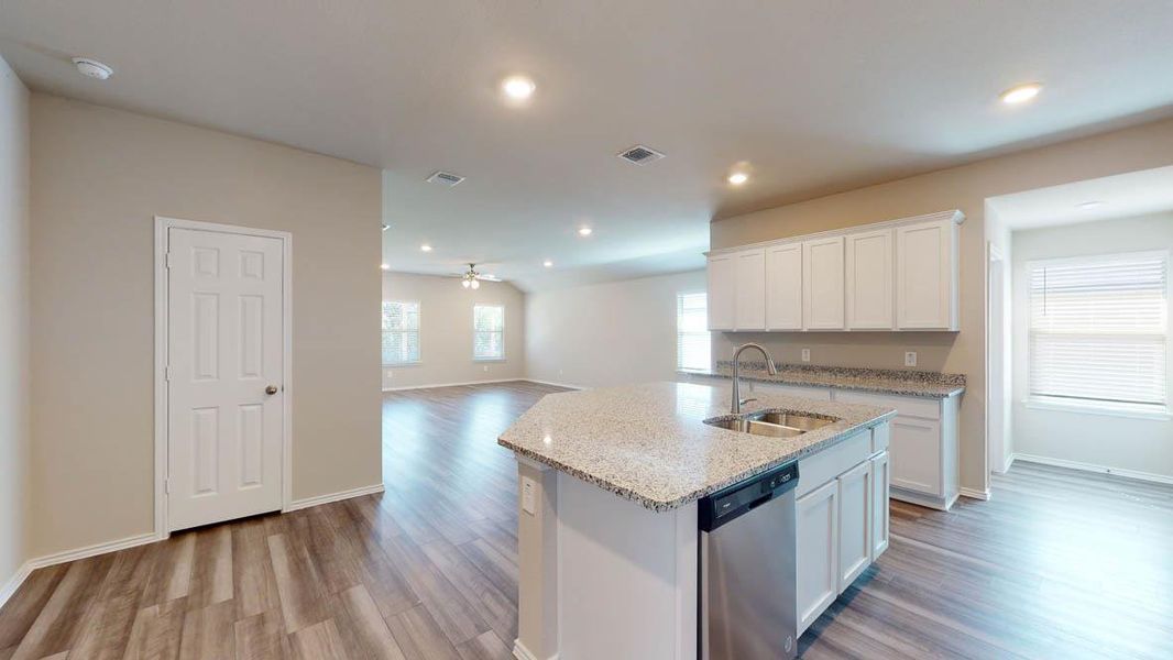 Kitchen with white cabinetry, a center island with sink, a ceiling fan, open floor plan, and dishwasher