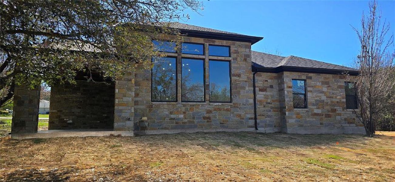 View of home's exterior featuring Oklahoma stone, and oversized windows View of home's exterior featuring Oklahoma stone, and oversized windows