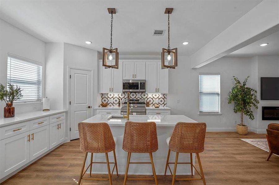 Kitchen featuring white cabinetry, appliances with stainless steel finishes, and a center island with sink