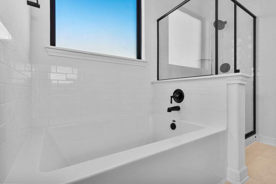 The primary bath feels indulgent and refined, featuring a soaking tub, separate shower, and glossy finishes.