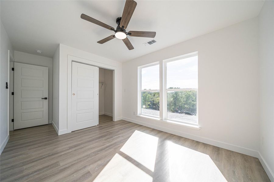 Unfurnished bedroom with a ceiling fan, a closet, and light wood-type flooring