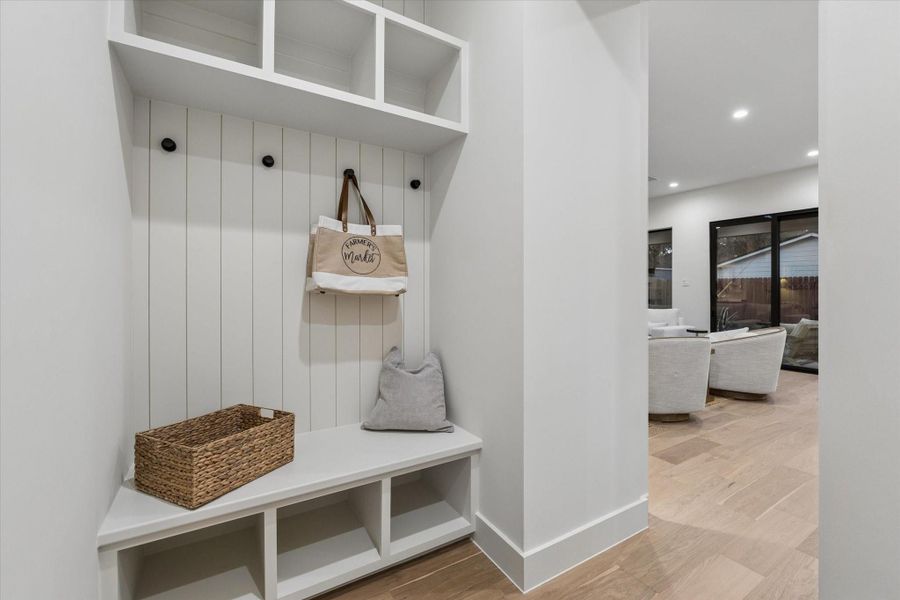 Located just off the garage, the mudroom offers bench seating, open shelving, hooks, and a charming shiplap wall—perfect for staying organized.