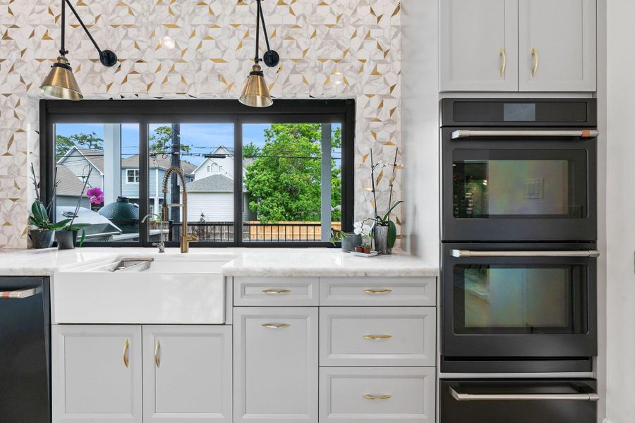 This kitchen features a Modern farmhouse sink with double ovens. The window slides open up allowing for easy access to food and utensils to the outside door patio. This kitchen features a Modern farmhouse sink with double ovens. The window slides open up allowing for easy access to food and utensils to the outside door patio.