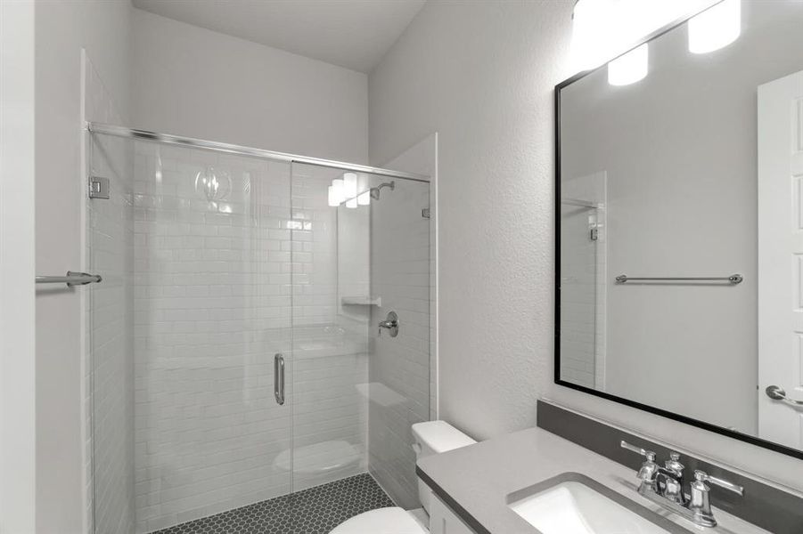 Bathroom with vanity, a shower with shower door, and toilet