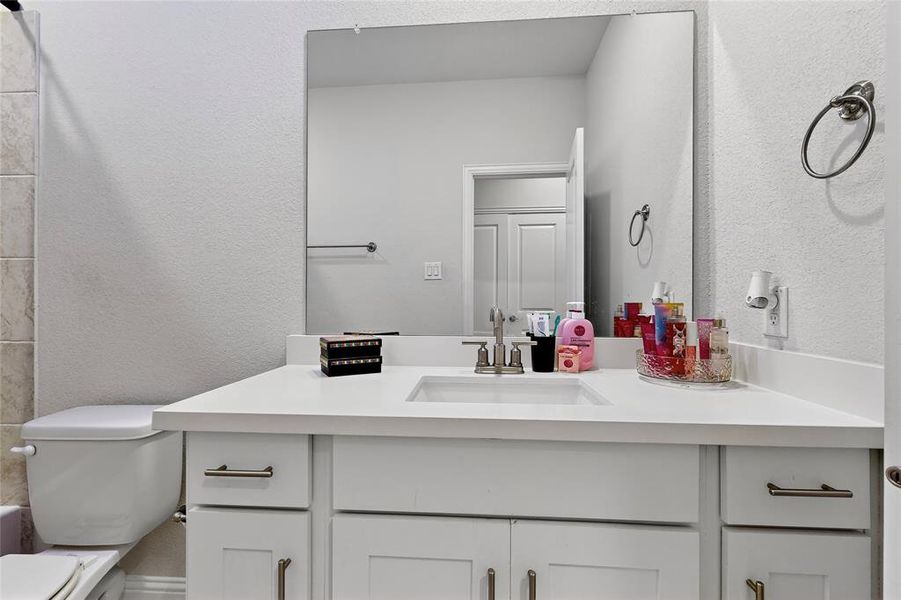 Bathroom with a textured wall, vanity, and bathing tub / shower combination