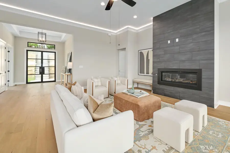 A refined living space features a tiled fireplace and light wood floors, perfect for relaxation.