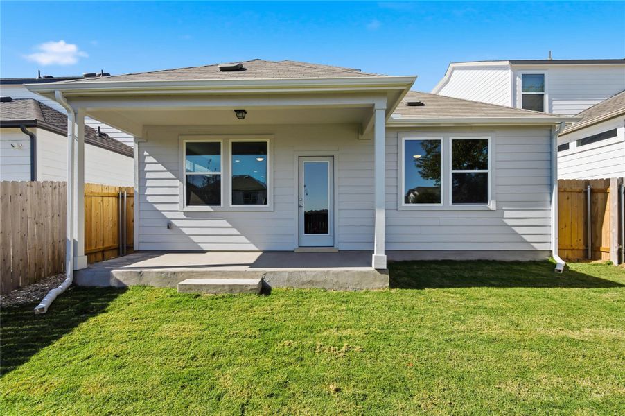 Rear view of house featuring a fenced backyard, a patio area, and roof with shingles