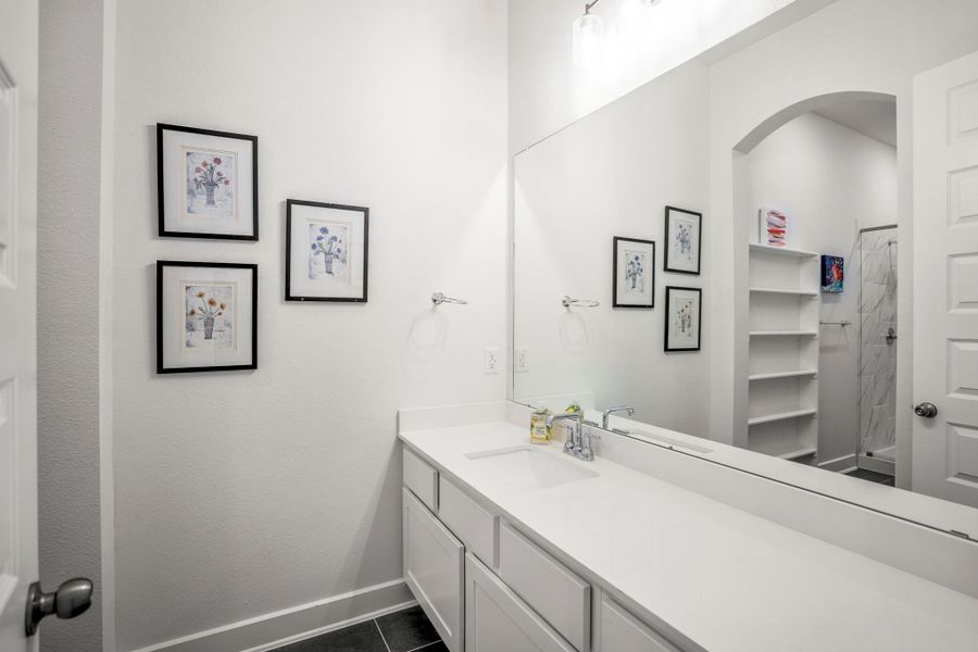 1st floor guest suite sleek and stylish bathroom with a walk-in shower, additional shelving and a walk-in closet.