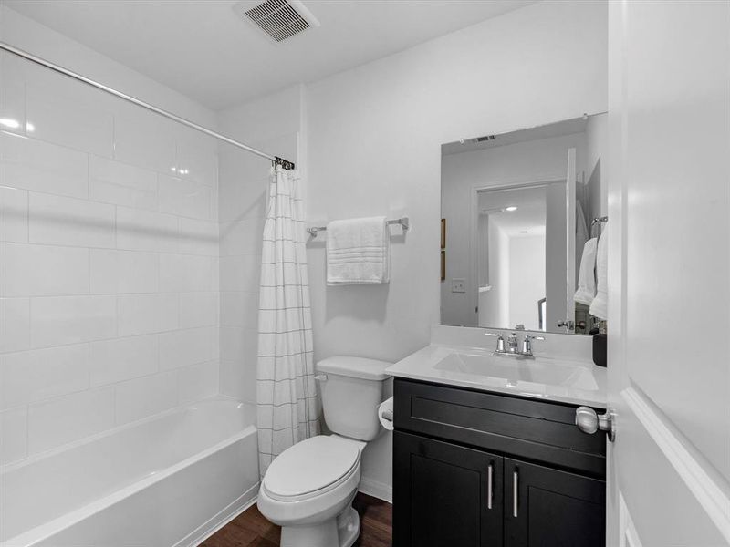 The secondary bath features tile flooring, dark stained cabinetry and dark stained countertops and a shower/tub combo. Perfect for accommodating any visiting family and friends.