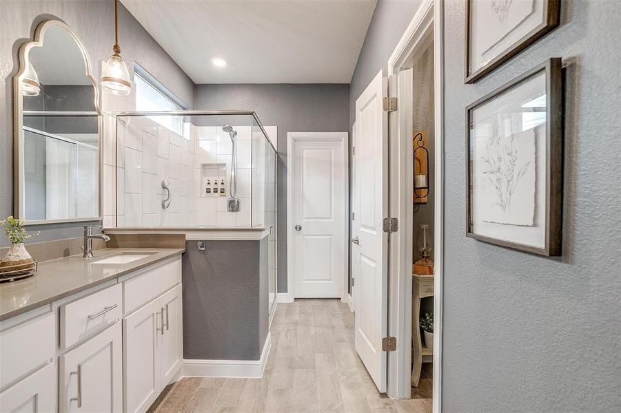 Full bathroom with a textured wall, wood finished floors, a shower stall, and vanity