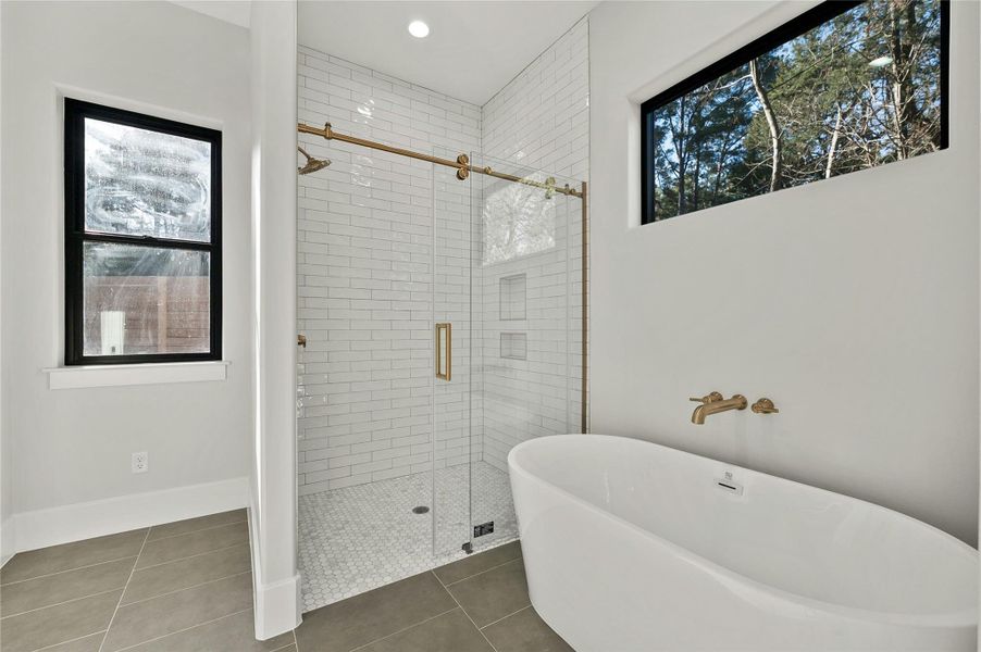 Bathroom featuring a wealth of natural light, plus walk in shower, and tile patterned flooring