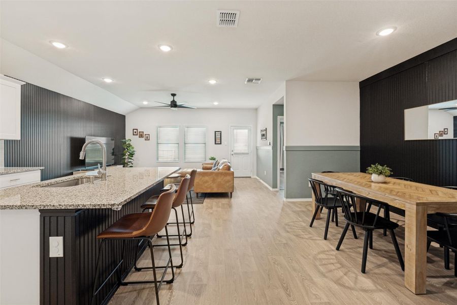An open-concept living space integrates a stylish kitchen island with granite counters, dining area, and living room.