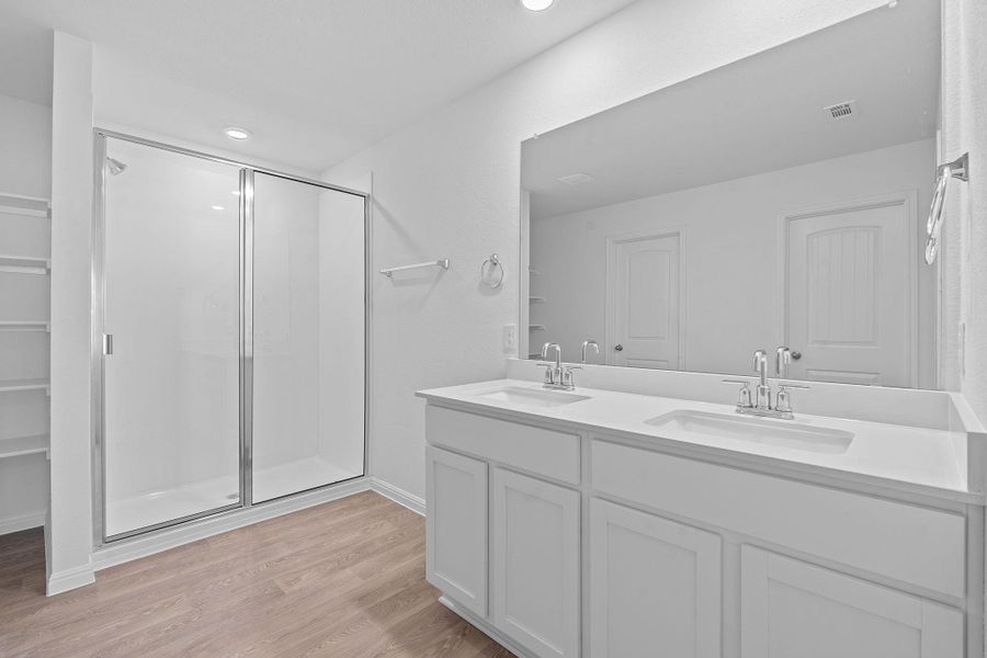 Bathroom featuring light wood finished floors, a stall shower, double vanity, and recessed lighting Bathroom featuring light wood finished floors, a stall shower, double vanity, and recessed lighting