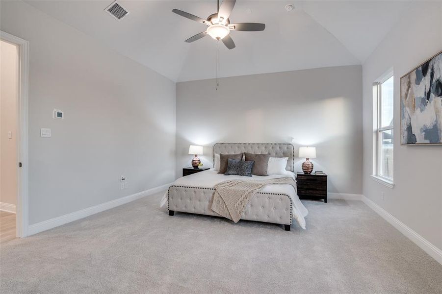 Bedroom with ceiling fan, multiple windows, light carpet, and vaulted ceiling