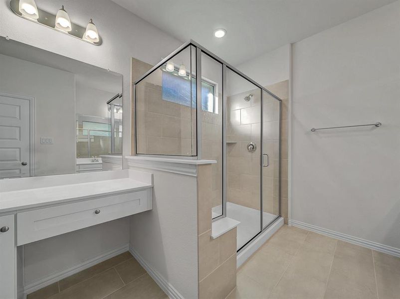 Bathroom with tile patterned floors, a shower with door, and vanity