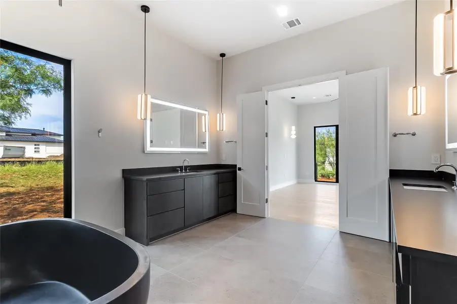 Full bath featuring vanity, a freestanding tub, and tile patterned flooring Full bath featuring vanity, a freestanding tub, and tile patterned flooring