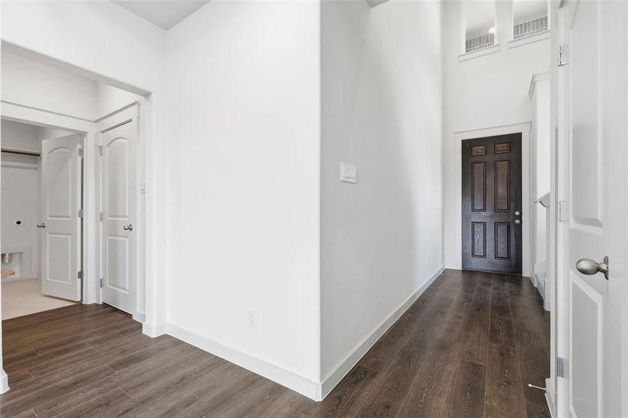 Hall featuring dark wood-type flooring and a high ceiling Hall featuring dark wood-type flooring and a high ceiling