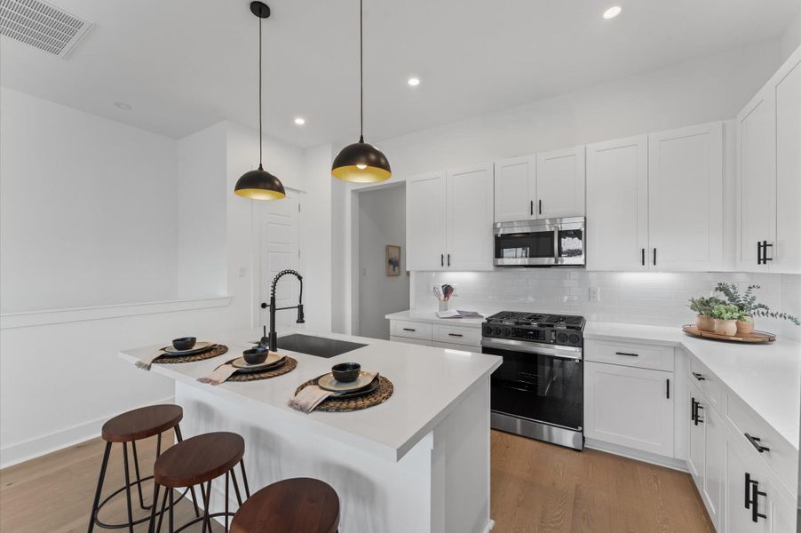 This centrally positioned kitchen island serves as a stylish anchor within the open-concept layout, offering clear sightlines to the dining area, living space, and the balcony beyond. Its placement encourages seamless interaction, whether prepping meals or entertaining guests, while natural light pours in through the nearby French doors. The island’s sleek design and functional surface make it a hub of activity tying together comfort and sophistication.