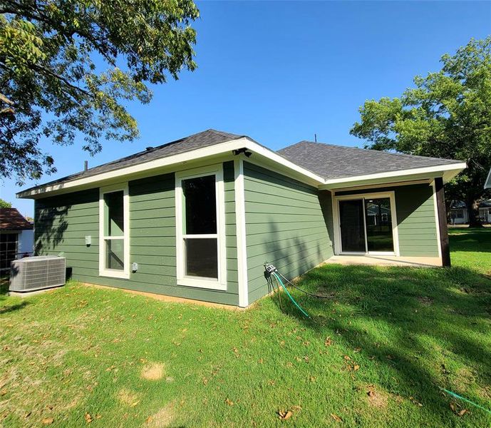 Rear view of property with a lawn and cooling unit