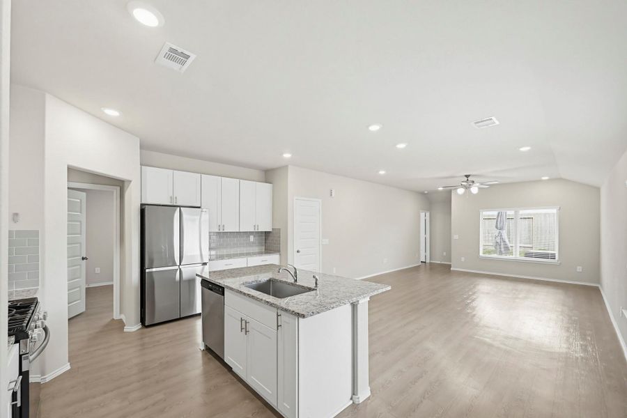 Open-concept living. The kitchen, dining, and living area shine with vinyl plank flooring and recessed lighting.