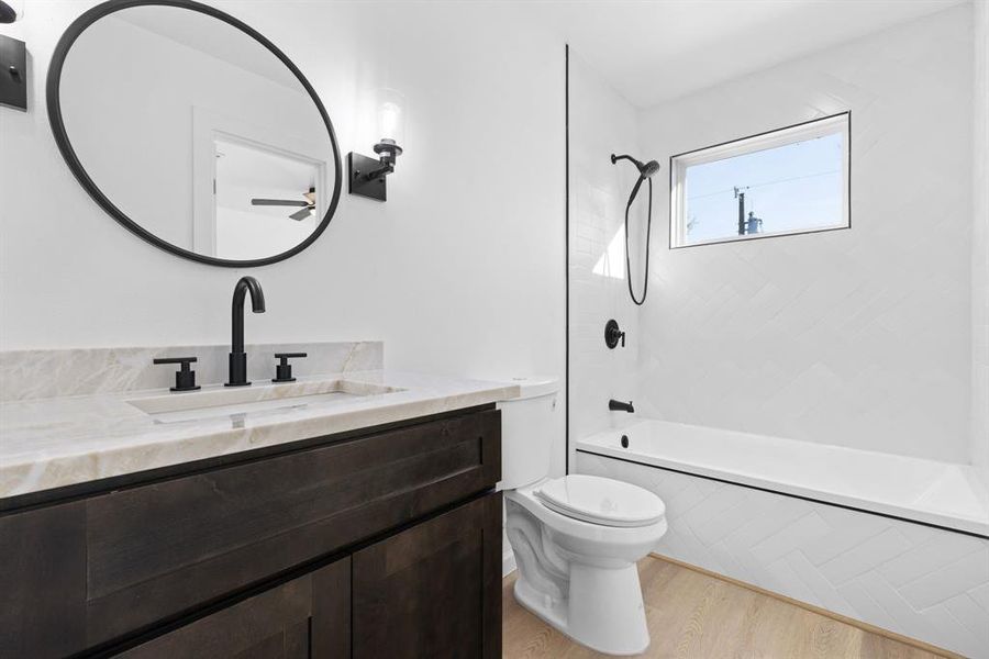 Full bathroom featuring tiled shower / bath, vanity, wood-type flooring, and toilet