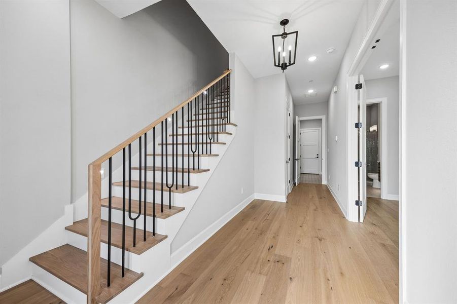 Staircase featuring hardwood / wood-style flooring and a chandelier Staircase featuring hardwood / wood-style flooring and a chandelier