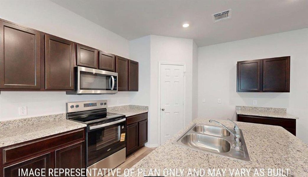 Kitchen featuring an island with a double basin stainless steel sink, granite-style countertops, dark wood cabinetry, a stainless steel electric range, and an over-the-range microwave