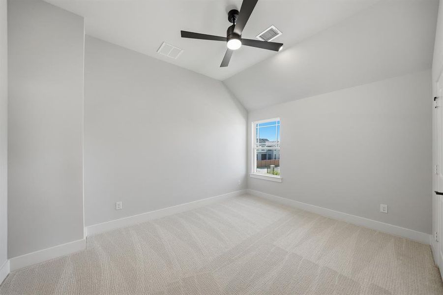 Empty room with light carpet, lofted ceiling, and a ceiling fan