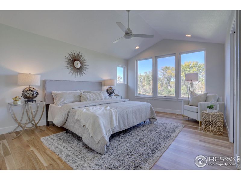 Primary bedroom has hardwood floors and vaulted ceilings